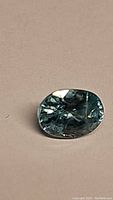 Close-up photo of the natural lagoon blue zircon gemstone showing oval cut and clarity characteristics under light.
