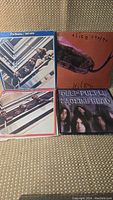 Four classic rock vinyl albums arranged on carpet surface showing front covers: Alice Cooper Killer, Deep Purple Machine Head, two Beatles Anthology albums with 1967-1970 in blue and 1962-1966 in red edge designs.
