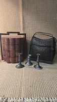 Photo shows antique Chinese stacking lunch box with red and black design, Laotian black woven bamboo basket, and three silver-colored metal candlesticks.