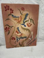 Full view of the handpainted silk batik artwork stretched on wooden frame, showing entire butterfly and floral design with faded brownish background.