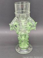 Front and side views of the pale green hand blown art glass vase with flared rim and pedestal foot, with animal head prunts attached to the body.