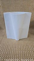 Front view of white porcelain vase showing pleated fan shape and smooth curved back