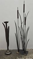 Two metal decor items: three cattail sculpture and a tulip-shaped candlestick holder.