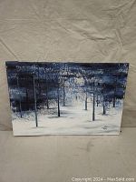 Front view of mixed media winter forest painting showing snow-covered ground, leafless trees, and a winter night backdrop in blues and whites.