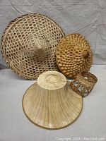 Photo of three handmade Asian sun hats in woven natural fibers with varying styles and sizes, arranged on a neutral background.