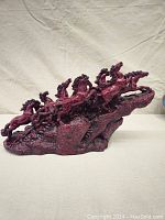 Full side view showing the group of running horses on raised rocky terrain base