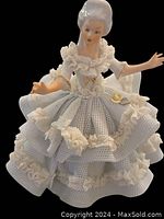 Front view of the porcelain figurine showing the woman in a detailed blue lace dress with white ruffles and gold accents.