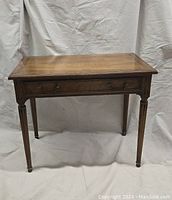 Front view of the vintage walnut writing desk showing diamond inlaid top and turned legs with brass caps