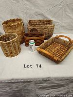 Collection of six wicker baskets and trays of various shapes, arranged on a cloth background with a soda can for scale.