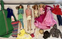 Four vintage 1960s dolls with an assortment of Barbie-labeled clothes, accessories, and a green zippered carrying case