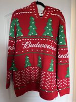 Front view of red Budweiser holiday sweater with green Christmas tree patterns and white Budweiser logo