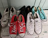 Five pairs of Converse sneakers in various colors and styles, showing overall condition and size.