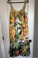 Full front view of the cotton dress in yellow tropical banana and fruit print with mixed fabric panels and ruffled tapered bottom hem.