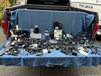 Full view of assorted electronics laid on a blue blanket including cords, chargers, and devices in the truck bed.