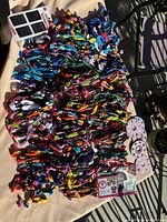 Photo showing a large pile of colorful DMC embroidery floss skeins along with black embroidery needles and floss organizing cards on a table.