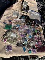 Overview of assorted beads, pearls, chains, strings, and various beading materials spread on cloth.