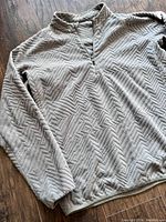 Front view of sage green fleece half-zip sweater showing full front and sleeve details, textured zigzag pattern visible.