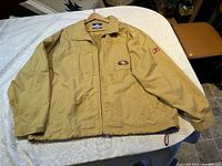 Full front view of the khaki-colored San Francisco 49ers jacket laid flat, showing overall condition and design