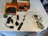 Top view photo showing Roku 2 device, remote, power cables inside the box, Firestick with remote, Chromecast device, and clamp-on flexible light laid out on a table.