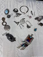 Top-down view of mixed assortment of sterling 925 pieces laid out on a textured white fabric background.