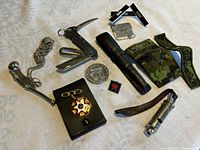 Full view of lot showing Bosun's pipe whistles, riggers multi-tool, badges, dog tags, patches, and other items on a light textured fabric.
