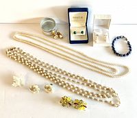 Full lot view showing all jewelry items laid out including pearl necklaces, earrings in boxes, bracelets, brooch and cluster earrings.