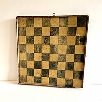 Front view showing black and tan checkered squares and wooden frame with slight damage.