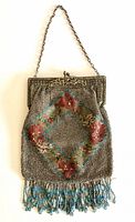 Full front view of the vintage beaded purse, shows chain handle, silver metal frame with embossed floral design, and main beaded body with floral diamond pattern and blue fringe.