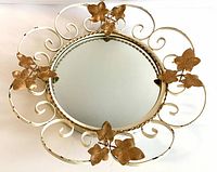 Full view of the vintage convex mirror showing white metal frame with copper leaves and scroll design.