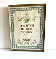 Full front view of the framed vintage cross stitch piece with floral border and central text