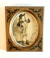 Full view of the vintage wooden frame with oval glass showing the little girl in cowgirl attire and autograph.
