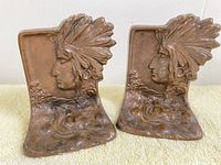 Pair of antique Native American Indian head copper bookends side by side.