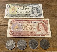 Photo showing front side of 1973 1 Dollar bill and 1974 2 Dollar bill with four Canadian silver dollars in a row.