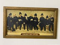Framed Carling's Red Cap Ale poster hung on wall, showing the full front image depicting nine policemen.