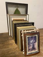 19 picture frames of various sizes stacked and arranged showing different styles and finishes.