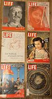 Top view of six vintage LIFE magazines with colorful covers featuring Stalin, Asian woman, historical scenes, and documents.