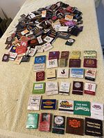 Large assortment of over 200 vintage match packs laid out on a flat surface showing many colorful designs and logos of Toronto based businesses and landmarks.