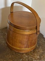 Front view showing the wooden firkin sugar bucket with attached lid and swing handle in vertical position.