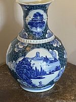 Front view showing the flared top, detailed blue landscape and floral patterns on white porcelain with crackle glaze.