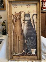 Full view of framed folk art painting depicting two cats on board.