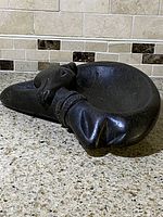 Side view showing reclining figure with detailed face and arm resting along bowl rim.