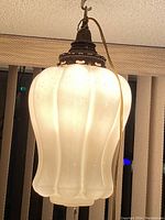 Front view of the peach lustre art glass swag lamp showing the scalloped glass globe, hanging hook, and electrical cord.
