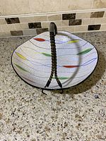 Top angled view of the vintage ceramic bowl showing colorful leaf patterns and wrapped dark handle.