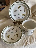Two plates with butterfly motifs and one bowl with bird illustration.