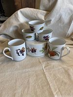 All six pieces arranged showing two mugs and four quiche souffle baking dishes with Evesham fruit and leaf designs.