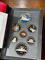 Coins displayed in the set, showing reverse side with detailed images celebrating the Centennial and Trans-Canada train, and various Canadian symbols.