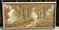 Full horizontal view of the framed oil painting showing a woodland landscape with autumnal trees and a dirt path under bright natural light.