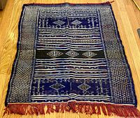 Full view of handwoven Kilim rug laid on wooden floor, showing entire pattern and fringes.