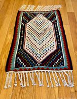 Top view of Persian Shiraz Kilim showing central geometric pattern with colorful small motifs and fringe ends.