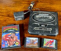 SEGA Genesis console, power adapter, and three game cartridges including Muhammad Ali Heavyweight Boxing in clamshell case, Splatterhouse Part 2, and Tengen Hard Drivin'.